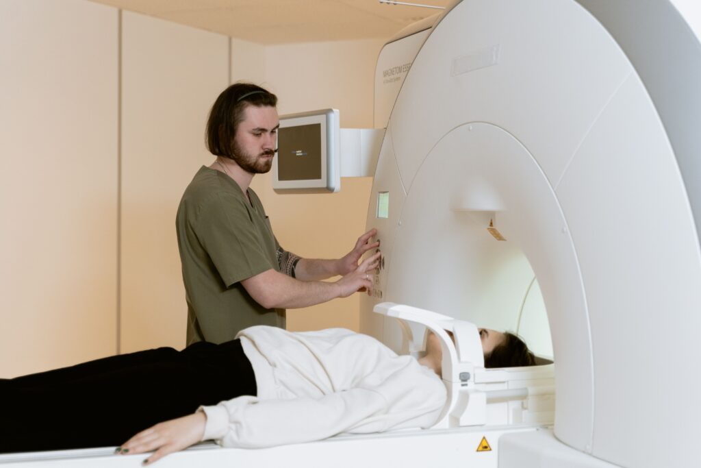 Medical technician operating MRI scanner for patient examination in healthcare setting.
